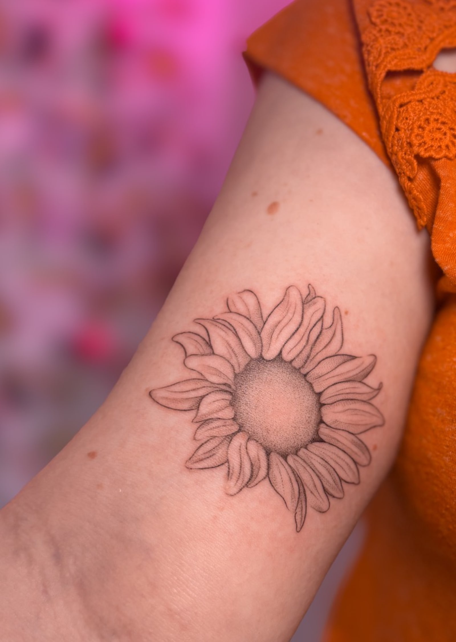 Healed fine line sunflower tattoo with dotwork centre on an upper arm