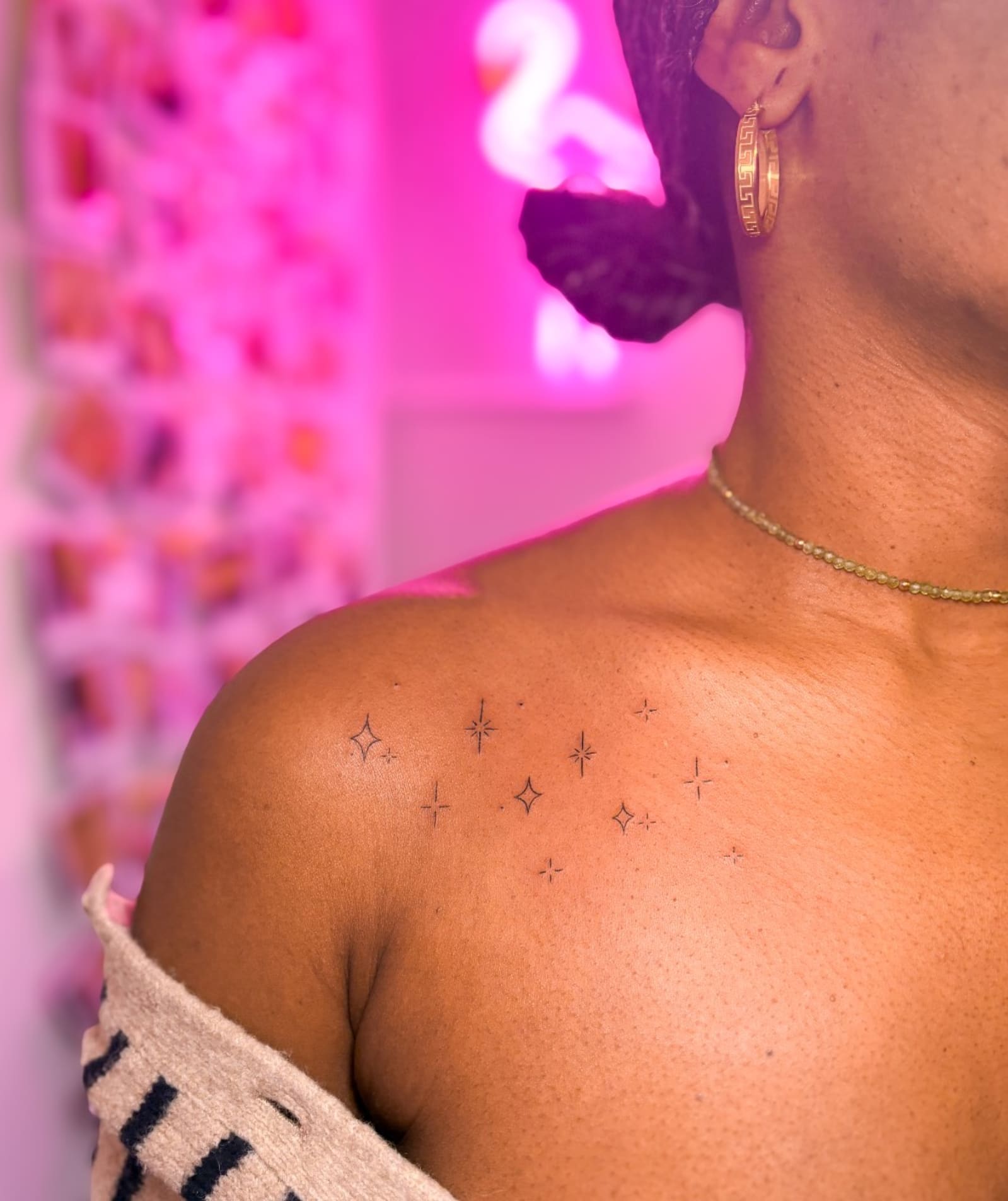 Scattering of tiny fine line sparkle and star tattoos across a collarbone