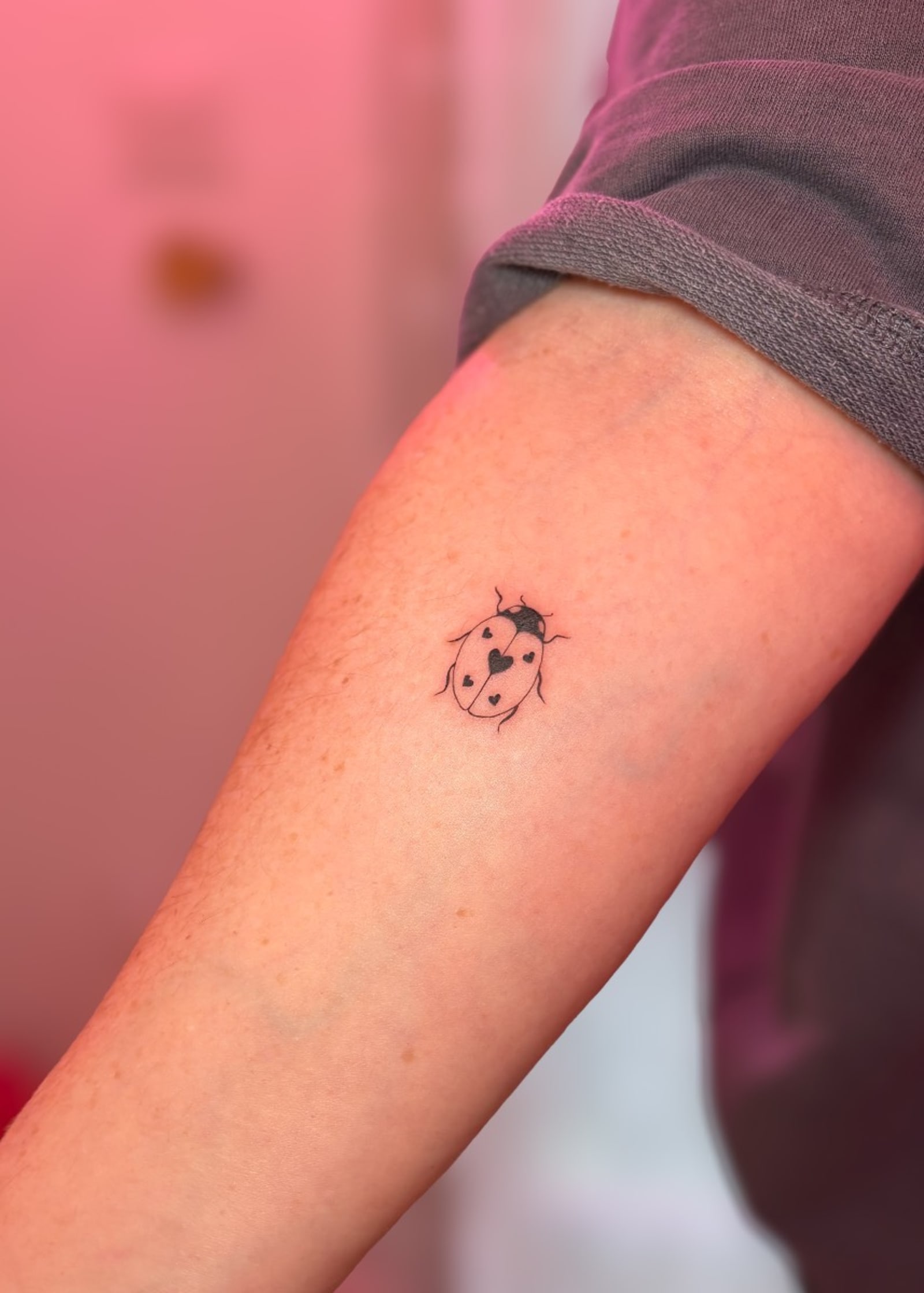 Miniature fine line ladybird tattoo
